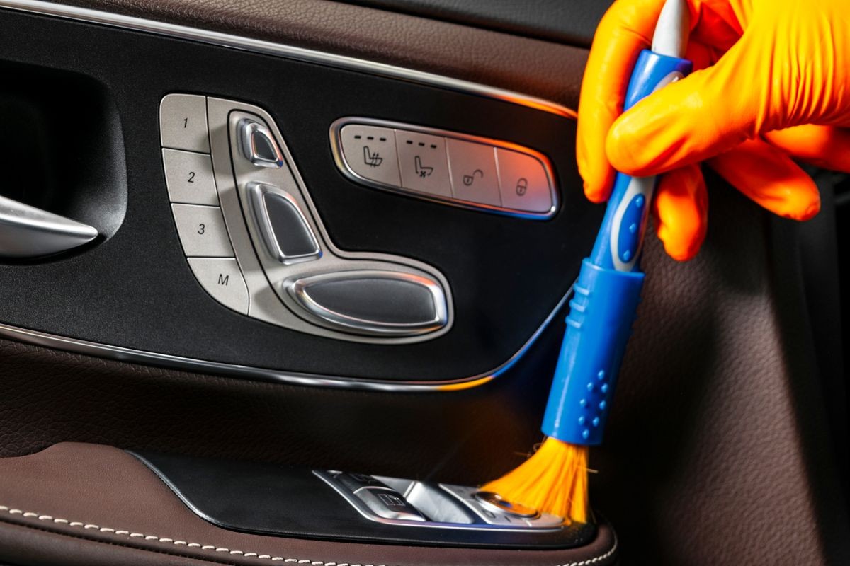 A man cleaning car with cloth and brush. Car detailing. Selective focus. Car detailing. Cleaning with brush. Worker cleaning. Brush and cleaning solution to clean.