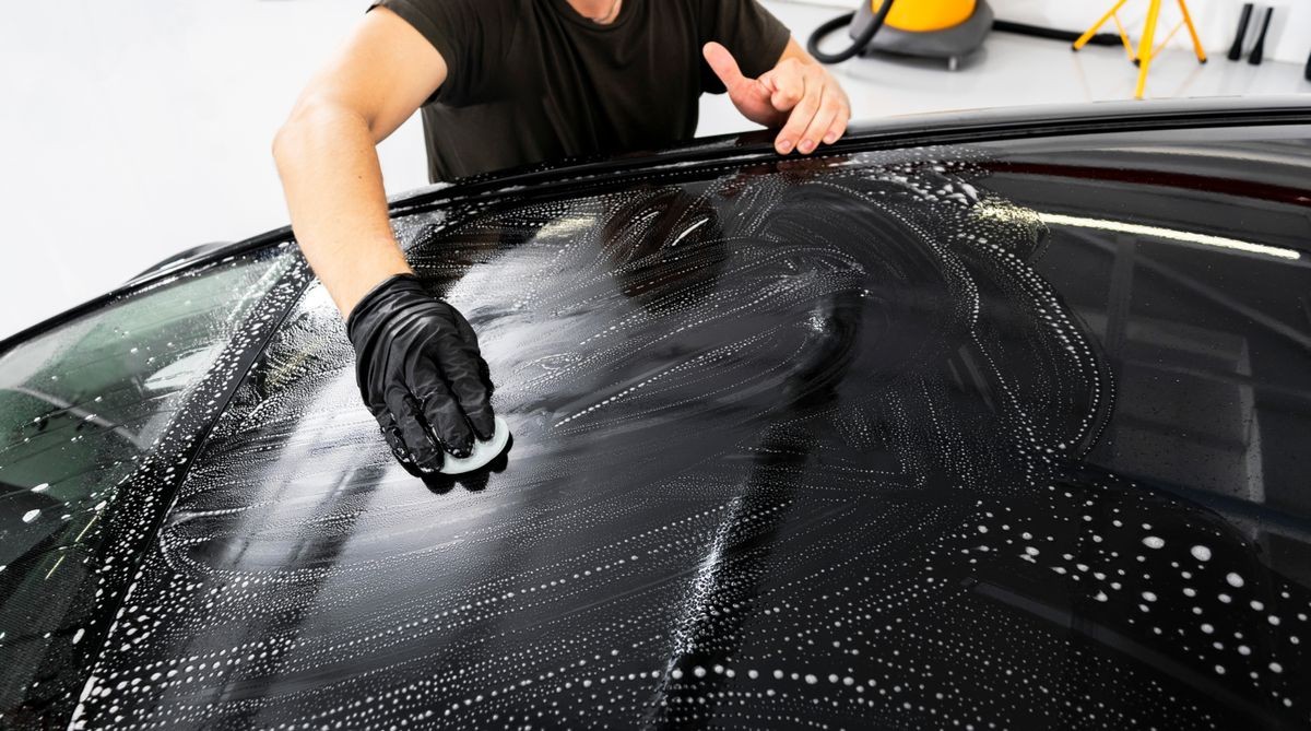 A man cleaning car with cloth. Car detailing concept. Selective focus. Car detailing. Cleaning with sponge. Worker cleaning. Cleaning solution to clean